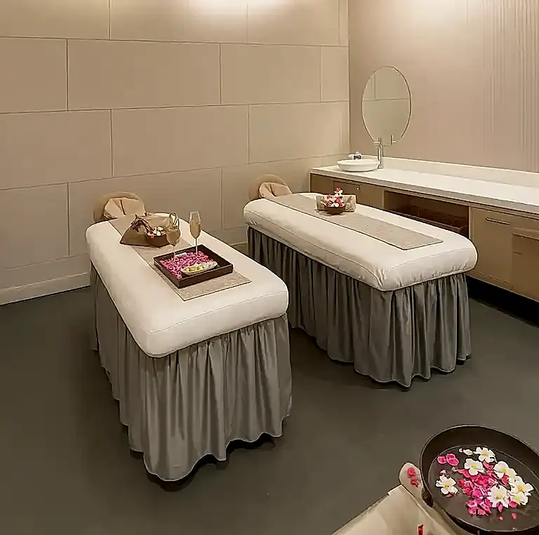 Elegant couple massage room with twin beds and flower arrangements at Tattva Spa Radisson Udyog Vihar Gurgaon.