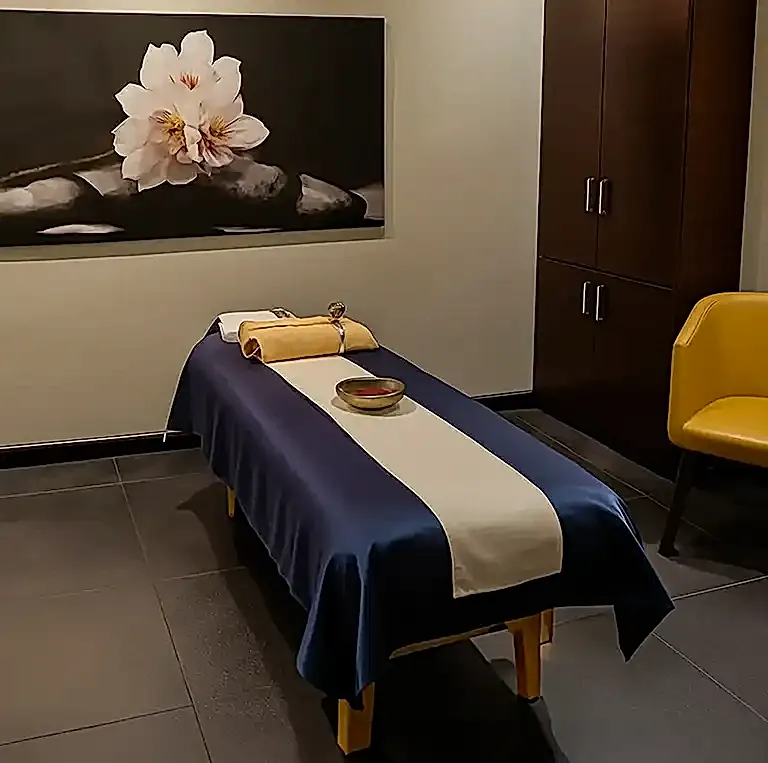 Private massage therapy room at Tattva Spa Hinjewadi Pune with neatly prepared massage bed, soft lighting, and floral artwork creating a serene relaxation space.