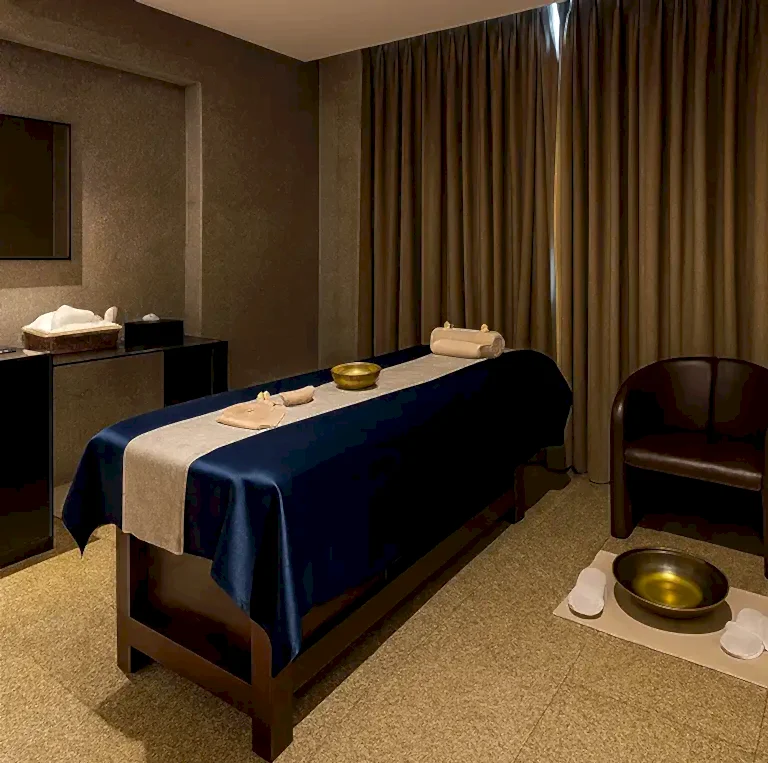 Private therapy room at Tattva Spa DoubleTree by Hilton MIDC Pune with a single massage bed, dim ambient lighting, brass spa bowl, and calming earthy interiors.