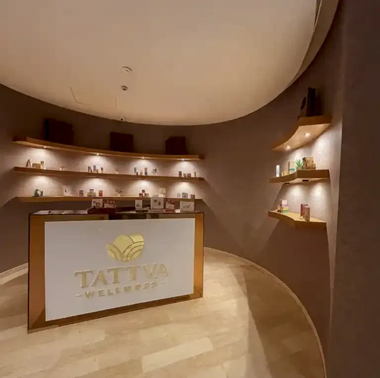 Tattva Spa reception area at Magarpatta Hadapsar Pune featuring warm lighting, wooden display shelves with wellness products, and a modern welcome desk creating a calming spa ambience.