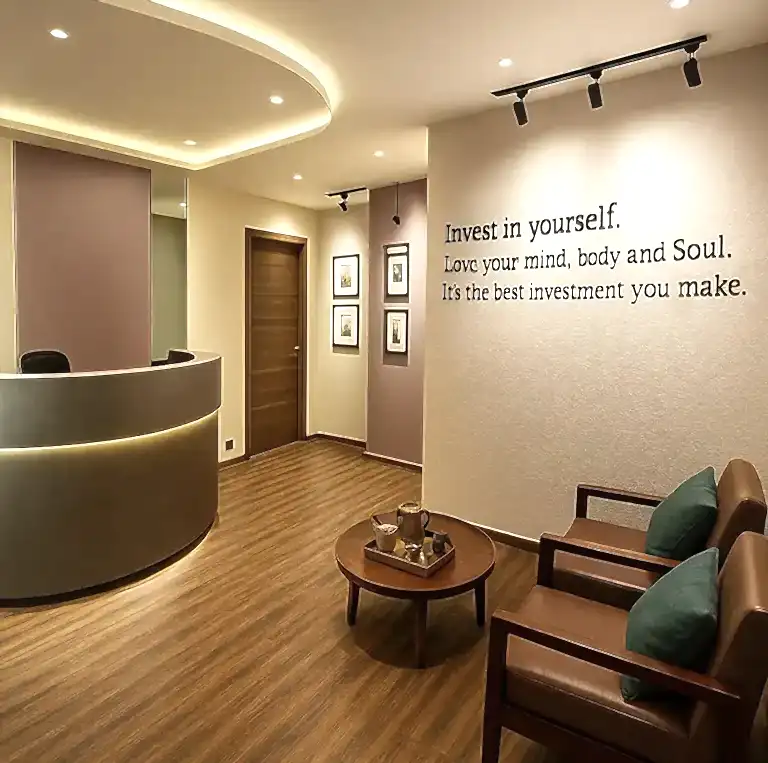 Modern reception and waiting area at Tattva Wellness Spa in A.S. Rao Nagar, Hyderabad, featuring soft lighting, wooden flooring, and a motivational wall quote promoting self-care and relaxation.